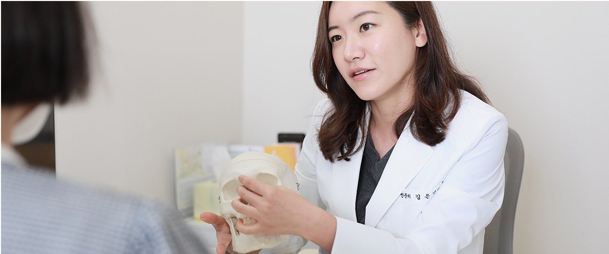 두개골 모형을 활용하여 환자와 상담 중인 의사